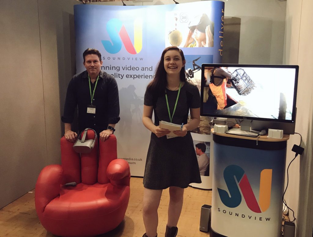 A man and woman standing in front of a business show setup