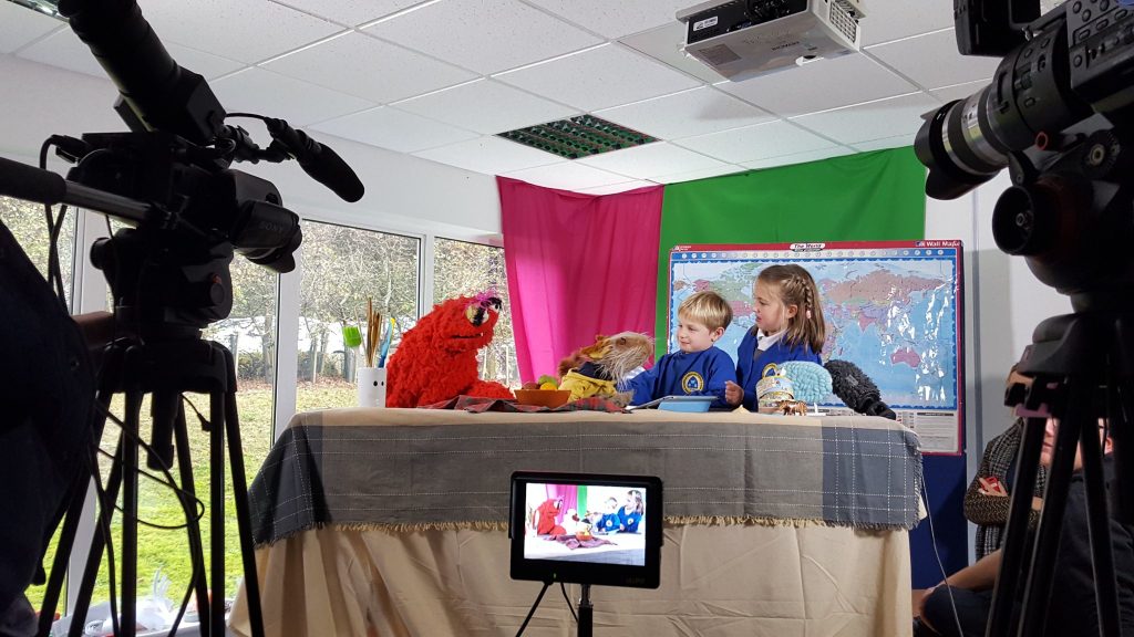 children interacting with puppets in front of a camera setup