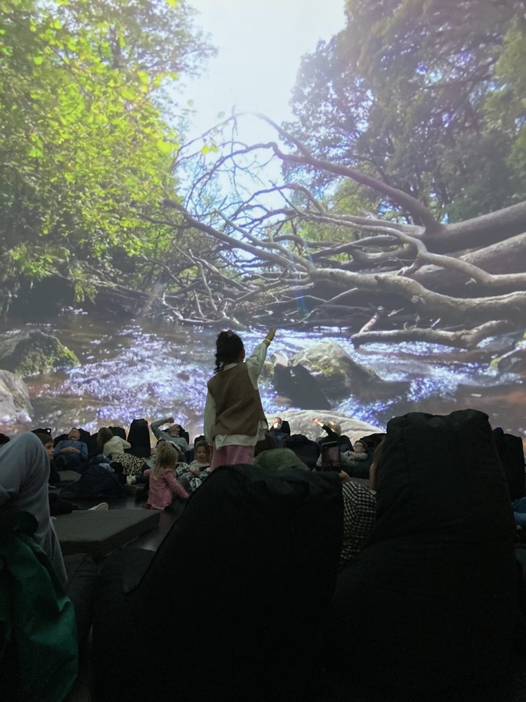Fulldome production at the Market Hall Plymouth: a child pointing at the Follow the Water film projected on the dome, with the audience in front