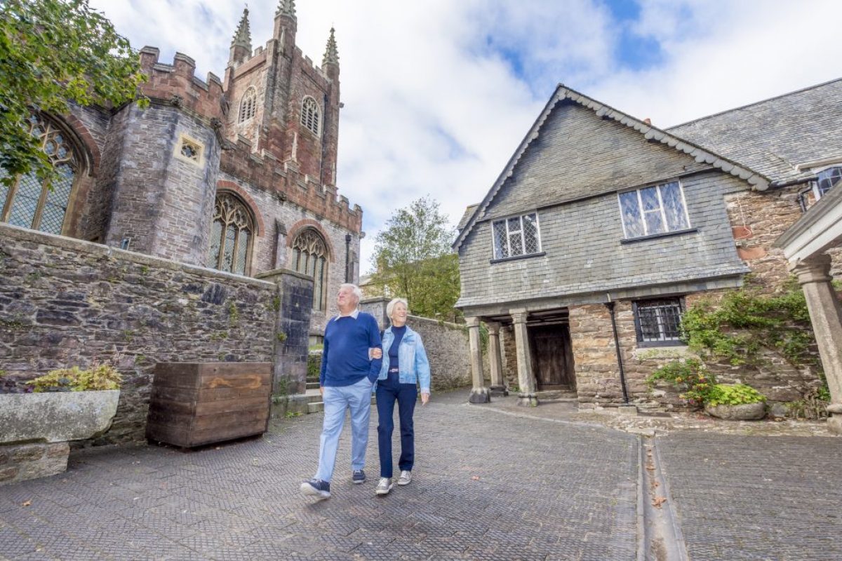 An older couple admiring their surroundings of a large church and house.